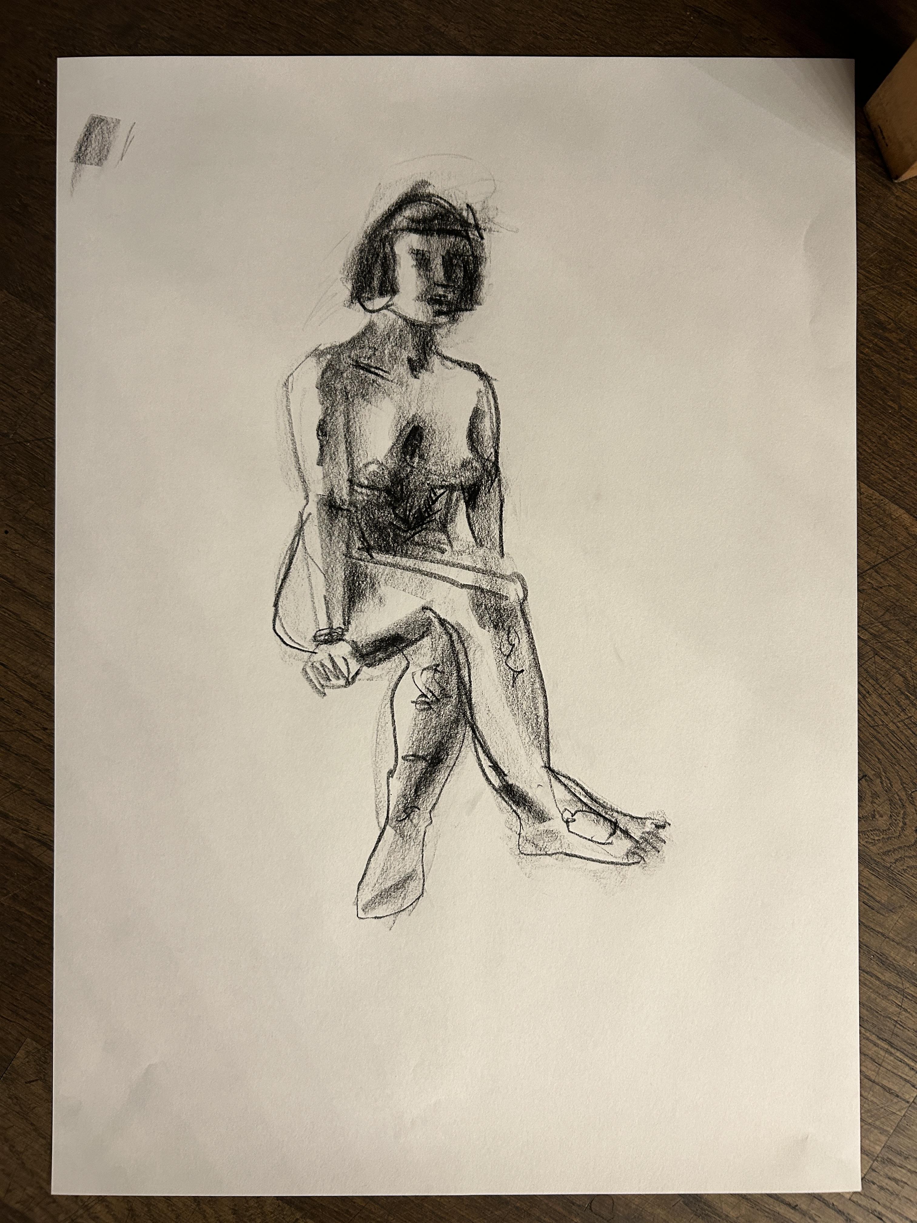Charcoal sketch of seated figure in relaxed pose on white paper